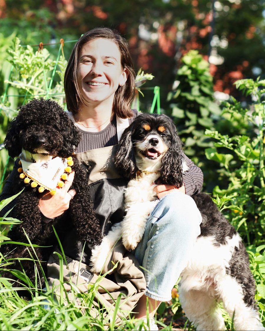 Haley crouching among tall garden plants with Wes in a bee bandana and Colt on her lap