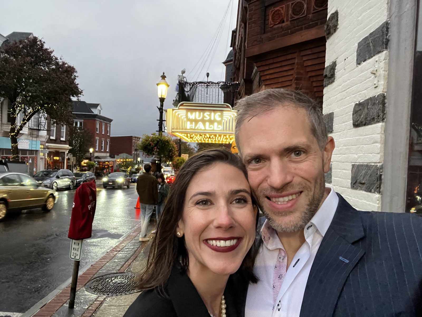 Haley and Michael dressed up in a selfie under a lit Music Hall marquee on a rainy evening