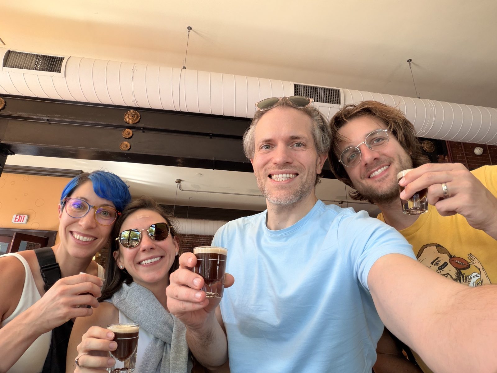 Haley, Michael, and two friends raising small glasses of espresso in a group selfie