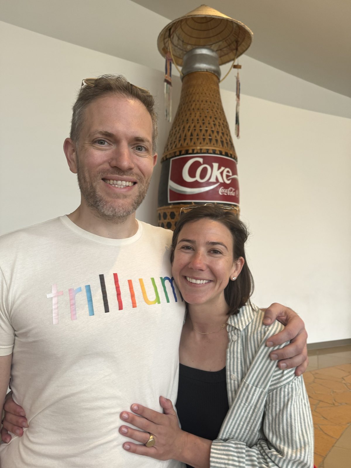 Haley and Michael in front of a giant woven Coke bottle wearing a conical hat