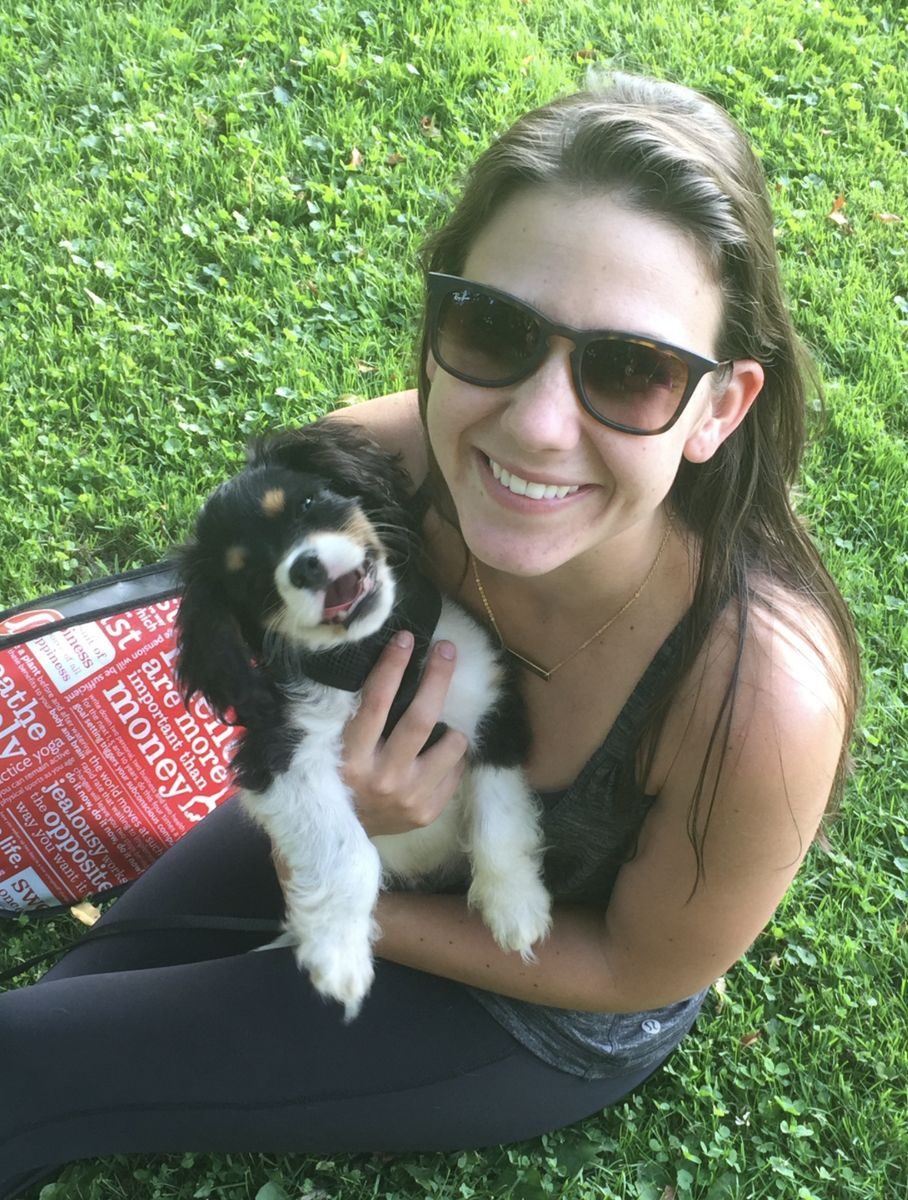 Haley in sunglasses on the grass, holding Colt as a small puppy