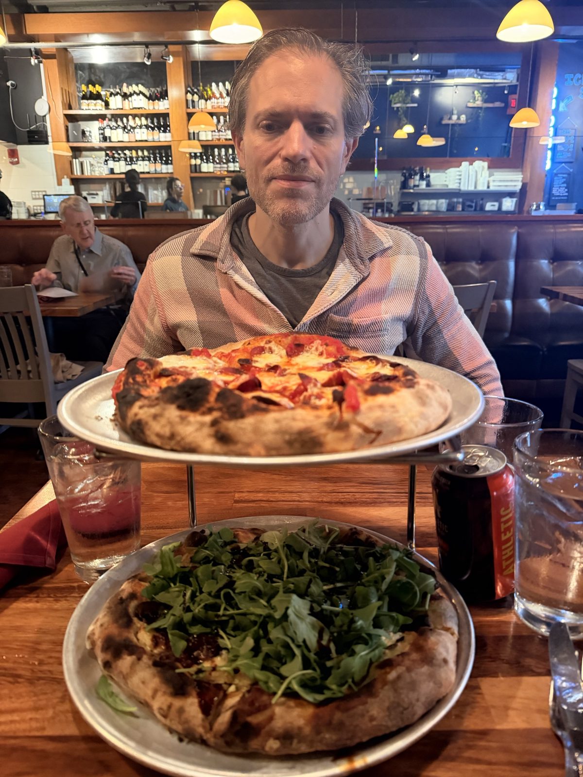 Michael behind two wood-fired pizzas, one stacked on a stand above the other