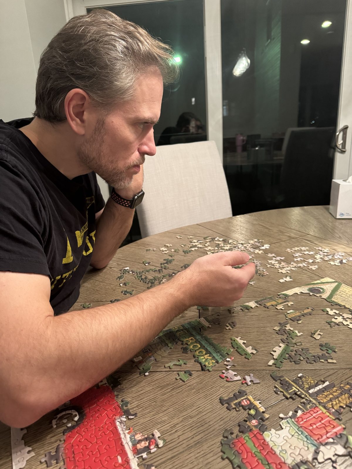Michael leaning over a half-finished jigsaw puzzle at the dining table