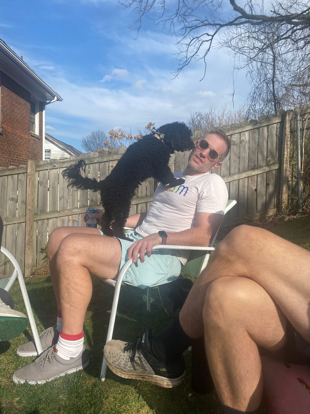 Michael relaxing in a lawn chair in a backyard while Wes stands on his lap to give him a kiss